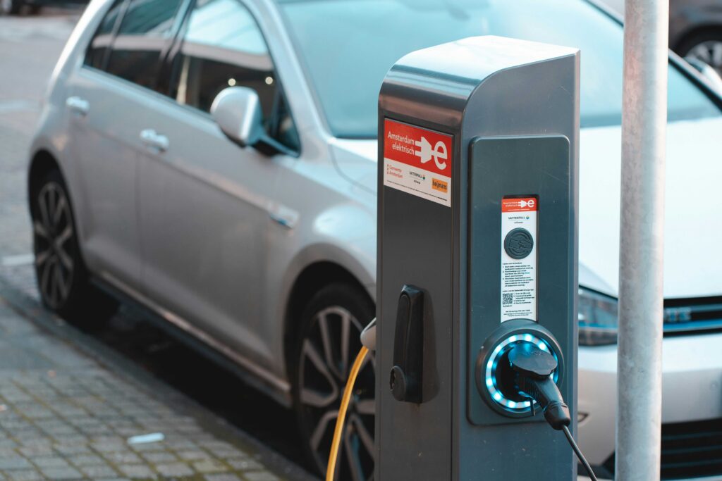 Solar power electric vehicle charging station with a plugged-in EV cable and a silver car parked nearby.