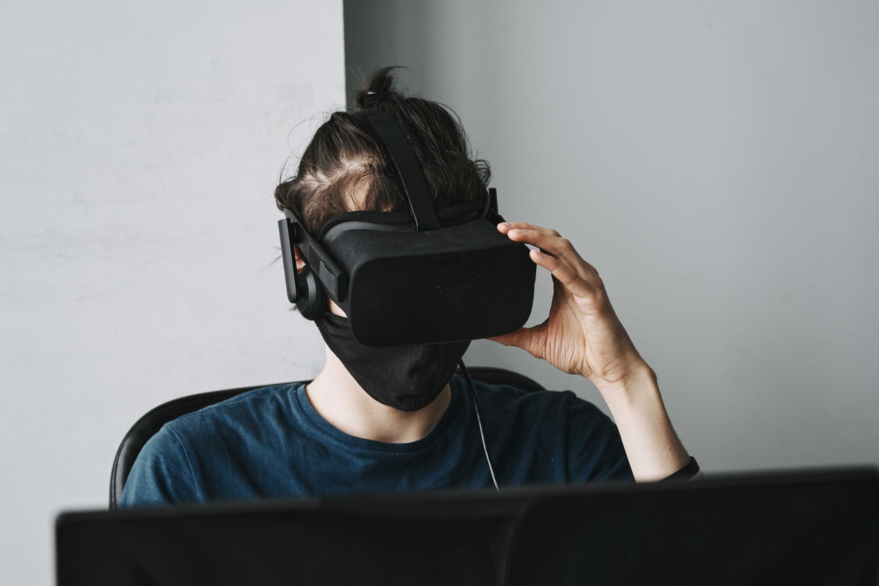 Person wearing VR headset and face mask while gaming on a laptop